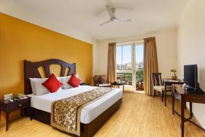 a hotel room with a bed and a desk and a window at Aloha On The Ganges by Leisure Hotels in Rishīkesh