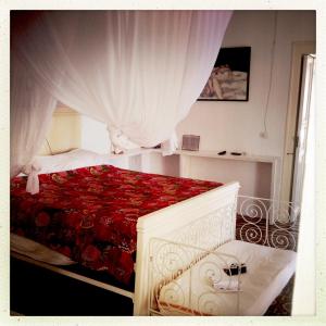 a bedroom with a red bed with a curtain at casa 3 archi in Alicudi