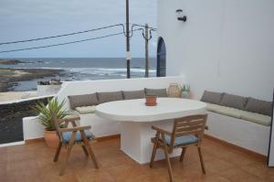 een witte tafel en stoelen op een balkon met uitzicht op de oceaan bij Casa Cabrera - 2 apartamentos con vistas al mar in Caleta de Caballo