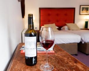 una botella de vino tinto y una copa en una mesa en Noel Arms - "A Bespoke Hotel" en Chipping Campden