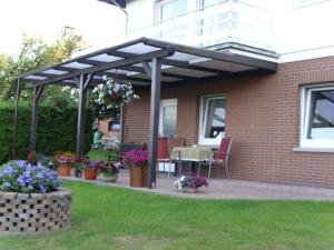 awning over a patio of a house with flowers at Ferienwohnung Gieseking in Porta Westfalica