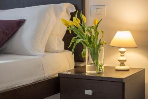 a vase of flowers on a table next to a bed at Emma & Olga Apartments -In the city Centre- in Florence