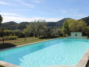 a large blue swimming pool with a fence and mountains in the background at Superb country house with private pool in Vaison-la-Romaine