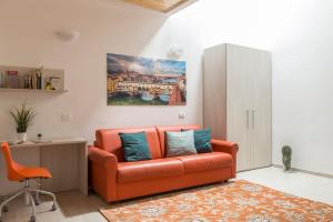 an orange couch in a living room with a painting on the wall at Emma & Olga Apartments -In the city Centre- in Florence