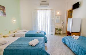 a hotel room with two beds and a television at Athena Rooms in Ios Chora