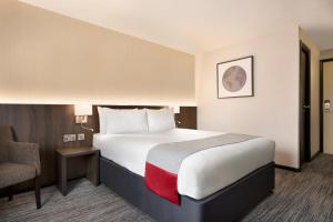 a hotel room with a large bed and a chair at Ramada Bristol West in Easton in Gordano