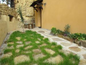 a patio with grass and a table next to a building at CASA RURAL El Refugio del Poeta in Triufé