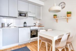 タンペレにあるHaave Apartments Tampereの白いキッチン(白いテーブルと椅子付)