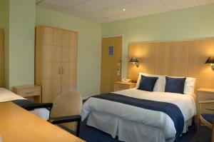 a hotel room with a large bed with blue pillows at Lysses House Hotel in Fareham