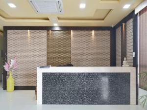 a reception desk in a room with a tile wall at Pemaling Lords Eco Inn Guwahati in Guwahati