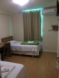 a room with two beds and a window with lights at Hotel Campos Plaza in Campos dos Goytacazes
