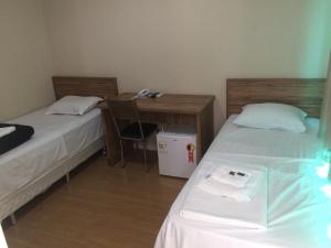a bedroom with two beds and a desk with a phone at Hotel Campos Plaza in Campos dos Goytacazes