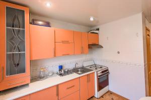 a kitchen with orange cabinets and a sink and a stove at Большая квартира на пр. МИРА in Salihorsk