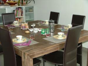 a wooden table with chairs and plates and glasses on it at Les Enselmes in Montagnieu