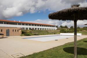 an empty pool with an umbrella and a building at Hotel Rural Santo Antonio in Arronches