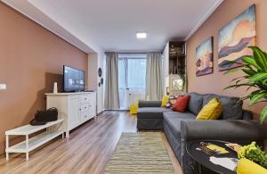 een woonkamer met een bank en een tv bij Sinaia Q Marie Apartment in Sinaia