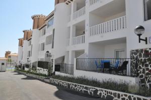 Una hilera de edificios de apartamentos blancos en una calle en Residencial El Pinet Beach, en La Marina