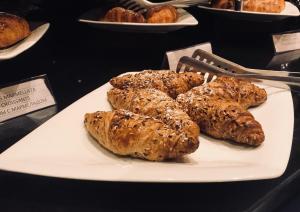 a white plate with croissants and other pastries at Hotel Principe di Piemonte in Rimini
