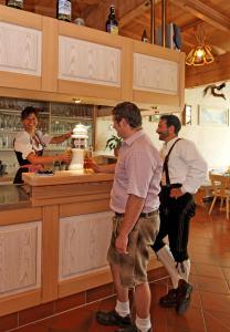 tres personas de pie en una cocina con una mujer detrás de un mostrador en Landhaus Maria Bed&Breakfast en Regen