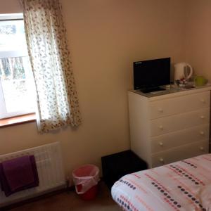 1 dormitorio con 1 cama y vestidor con TV en The Lodge Guest House, en Grain