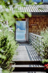 a wooden walkway leading to a house with the ocean at Seehotel Enzian in Weissensee