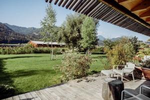 eine Terrasse mit zwei weißen Stühlen und einem Grasfeld in der Unterkunft Seehotel Enzian in Weissensee