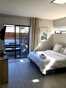 a bedroom with a large bed and a balcony at Lower Point Surf Studio in Jeffreys Bay