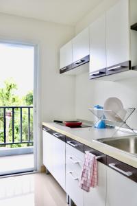 a kitchen with white cabinets and a large window at The View Condominium Suan Luang, Phuket Town in Phuket