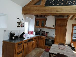 eine Küche mit Holzschränken und einem Tisch darin in der Unterkunft Les gîtes d'Herquetot "Les Genets" in Vasteville