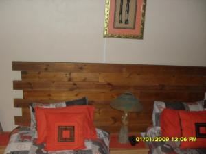 a bedroom with a wooden headboard and a bed with red pillows at Silvermoon in Nigel +12 photos