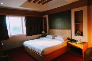 um quarto com uma cama grande e uma janela em The Rich Hotel em Nonthaburi