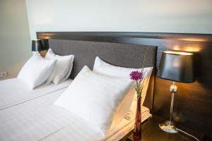 文尼察丘池尔酒店的一张带白色枕头的床和花瓶