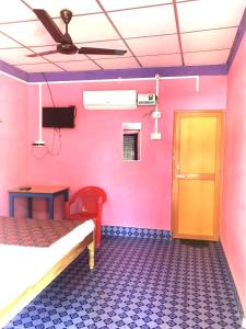 a bedroom with pink walls and a bed and a door at Blue Bird Residency in Neil Island