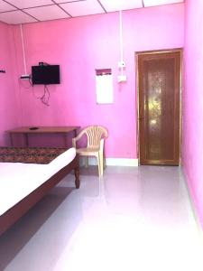 a pink room with two beds and a table and a chair at Blue Bird Residency in Neil Island