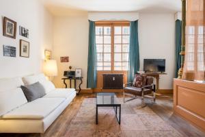 a living room with a white couch and a chair at Honorê - Suite Jacobins in Lyon