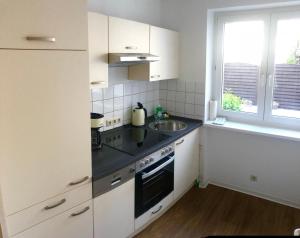 エアフルトにあるSuite Auenviertelの白いキャビネット、シンク、窓付きのキッチン