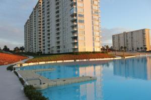 a large apartment building with blue water in front of it at Resort Laguna Bahía, Océano Piso 12 Algarrobo in Algarrobo