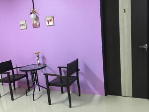 einen Tisch und Stühle in einem Zimmer mit einer lila Wand in der Unterkunft Maerim Hostel in Chiang Mai