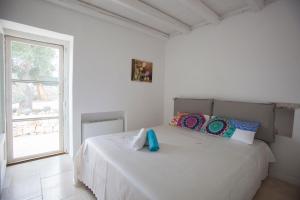 um quarto branco com uma cama com almofadas e uma janela em Trullo Oasi Santo Stefano - private pool em Castellana Grotte