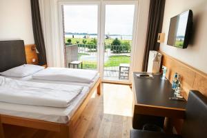 um quarto de hotel com uma cama, uma secretária e uma janela em Im-Jaich Hotel Bremerhaven em Bremerhaven