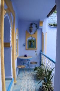 a balcony with a table and stools at Hôtel Dar Terrae in Chefchaouen