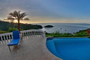 a blue chair sitting on a balcony overlooking the ocean at The Lighthouse Ocotal in Coco