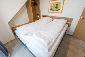 1 cama con sábanas blancas en una habitación en Hrimland Apartments, en Akureyri