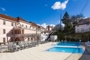 una casa con piscina di fronte a un edificio di INATEL Palace S.Pedro Do Sul a Termas de São Pedro do Sul