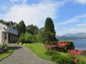 a house with a garden next to the water at Lochwood Guest House in Lochgoilhead