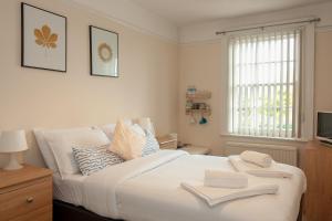 a bedroom with a white bed with two towels on it at The Jollys in Bootle