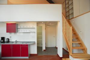 a kitchen with red cabinets and a staircase at GLS Studio Hotel Berlin in Berlin