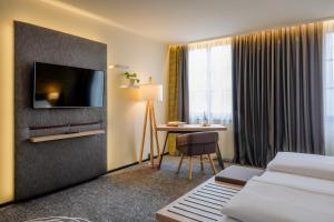 a hotel room with a bed and a desk and a tv at Mercure München City Center in Munich