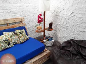 a blue bed in a room with a lamp and flowers at Villa Miracá Guest House in Maresias