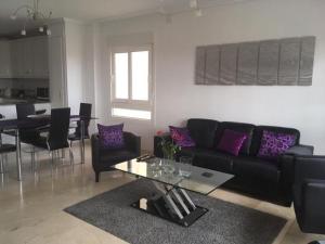 Una sala de estar con un sofá negro y una mesa. en Jumilla III, en Orihuela Costa